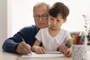 Menino novo e seu avô escrevendo em folha de papel