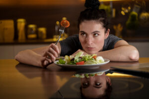 Mulher irritada olhando comida saudável tentando fazer dieta