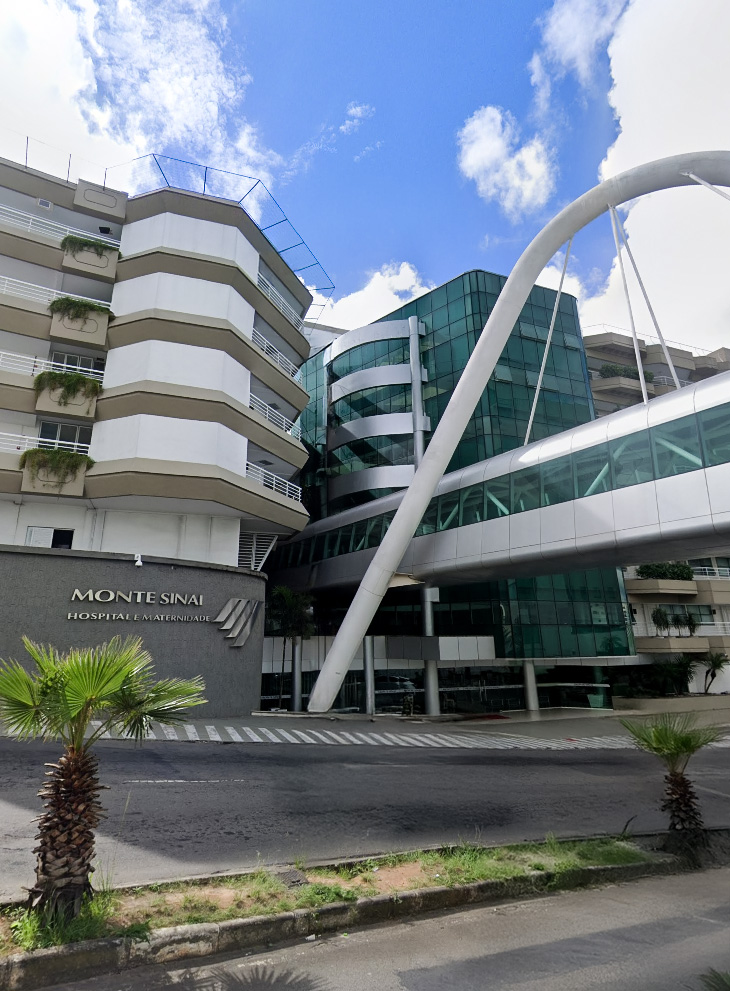 Fachada moderna do Hospital Monte Sinai em Juiz de Fora, destaque da rede credenciada CEDplan Saúde, com arquitetura envidraçada e passarela elevada.