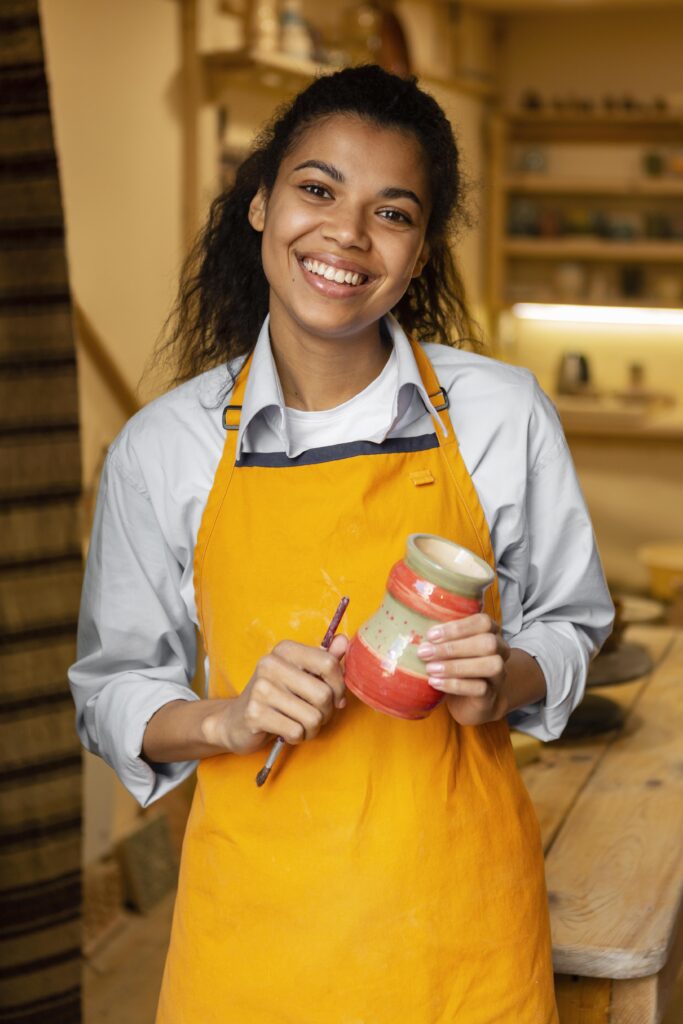 Artesã MEI sorrindo enquanto segura uma peça de cerâmica no ateliê, representando segurança e bem-estar proporcionados pelo plano de saúde em Juiz de Fora.