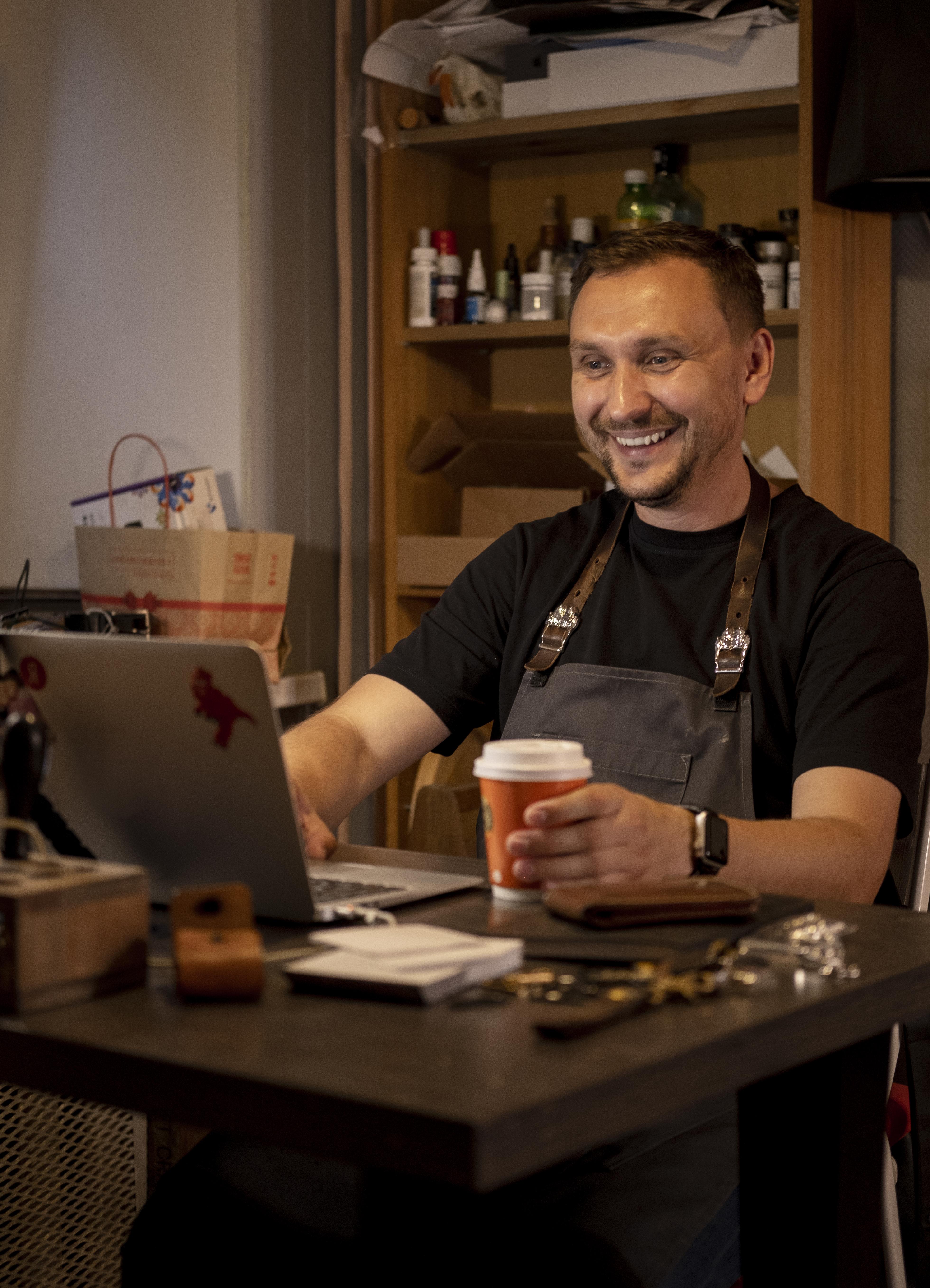 Microempreendedor individual de Juiz de Fora trabalhando no laptop enquanto toma café, simbolizando organização e gestão eficiente do MEI.