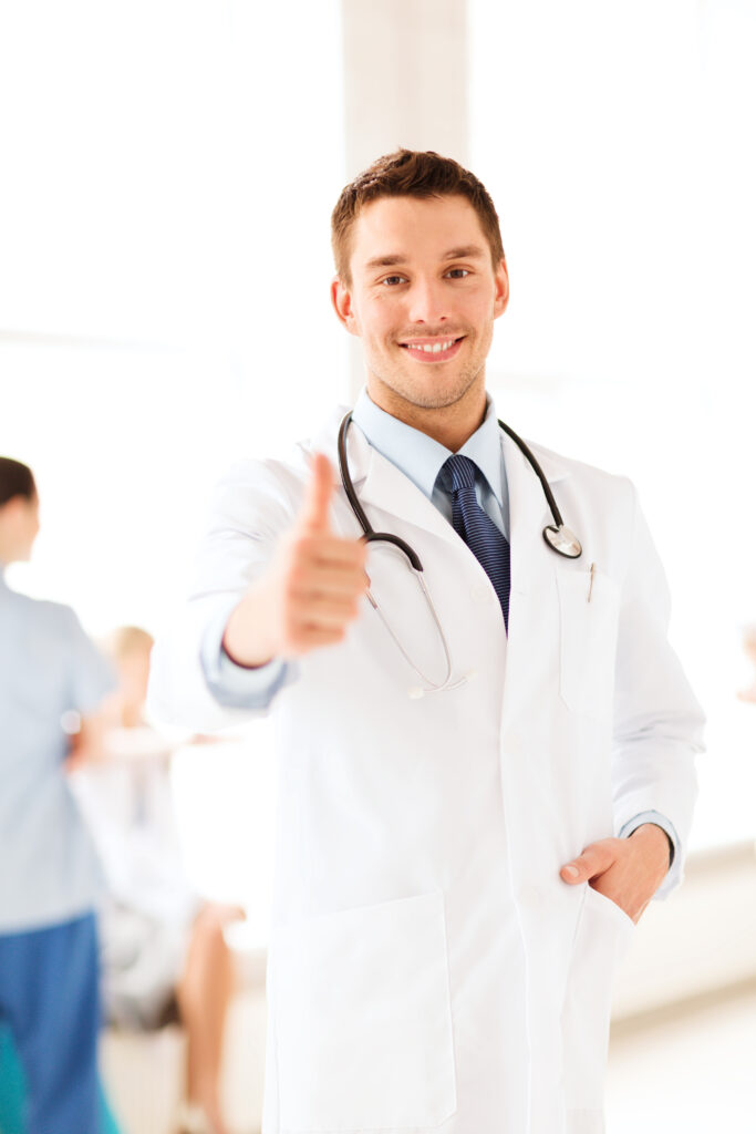 Médico sorridente com jaleco branco e estetoscópio, fazendo sinal de positivo em hospital credenciado pela CEDplan em Juiz de Fora